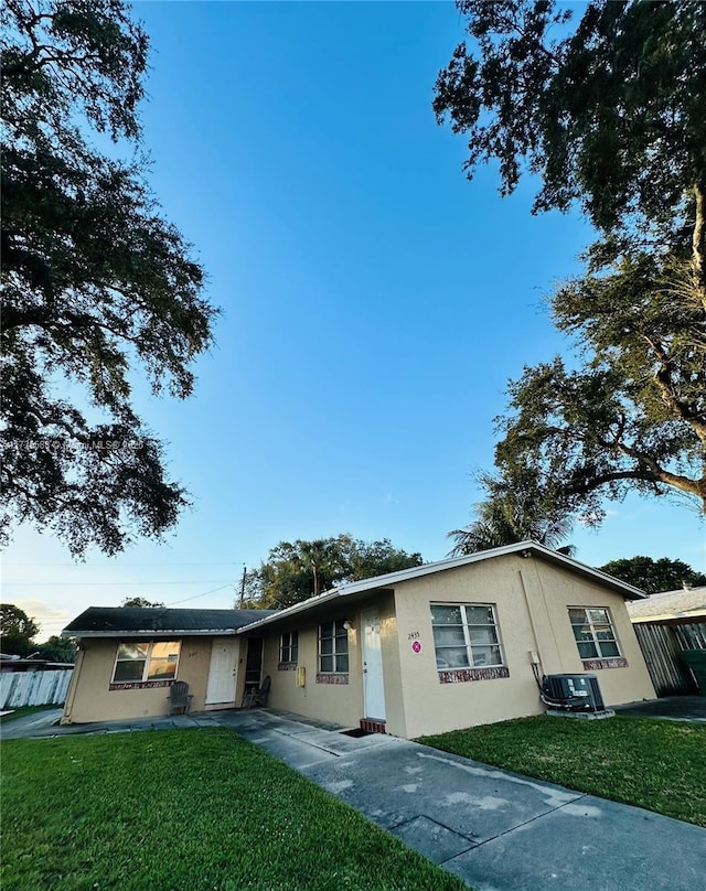 ranch-style house featuring cooling unit and a front lawn