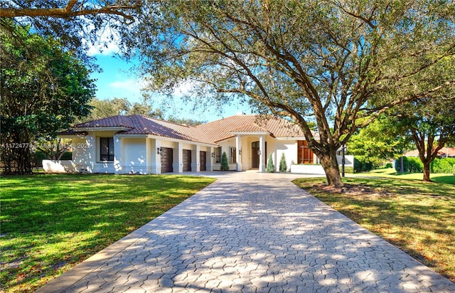 mediterranean / spanish house featuring a garage and a front lawn