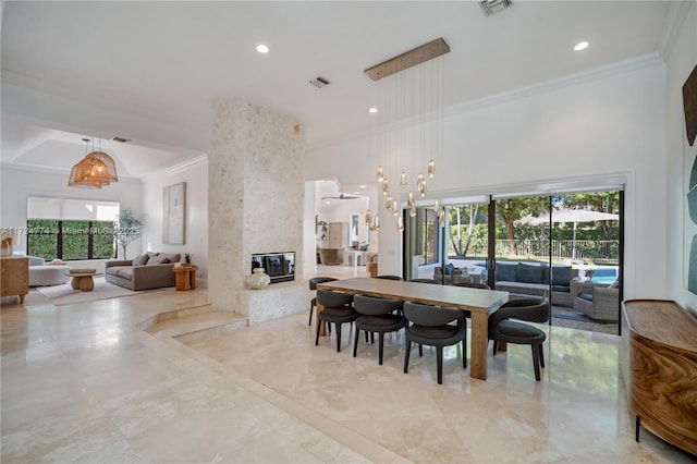 dining space featuring crown molding, a fireplace, and a towering ceiling