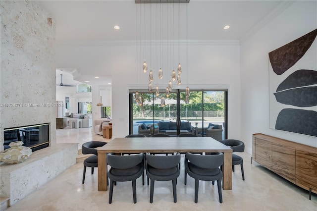 dining area with plenty of natural light, ornamental molding, a fireplace, and a high ceiling