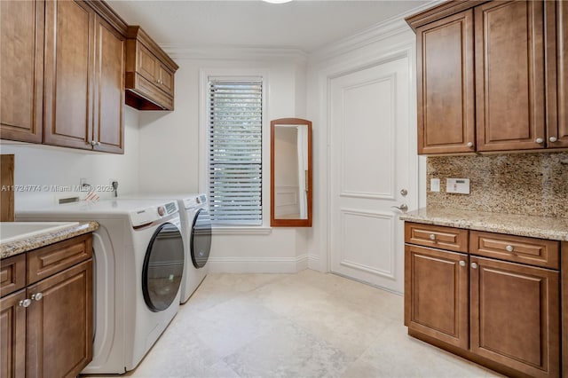 washroom featuring cabinets, ornamental molding, and washer and dryer