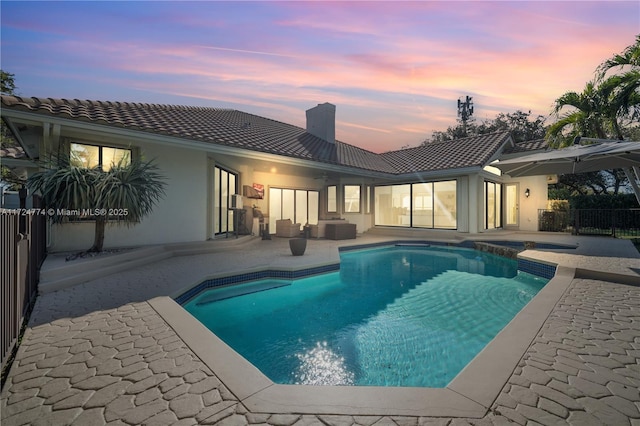 pool at dusk featuring a patio area