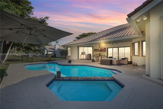 pool at dusk featuring a patio, outdoor lounge area, and ceiling fan