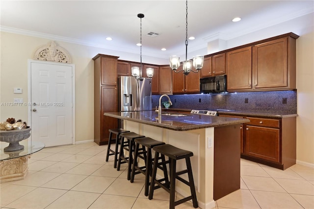 kitchen featuring pendant lighting, sink, stainless steel fridge, a breakfast bar, and an island with sink