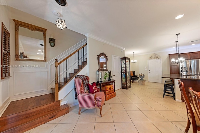 tiled foyer featuring ornamental molding and a notable chandelier