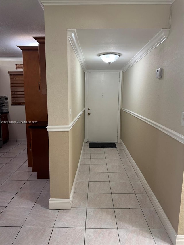 corridor featuring baseboards, light tile patterned flooring, and crown molding