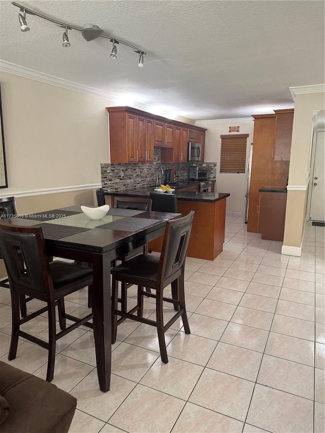 dining room featuring light tile patterned floors, ornamental molding, and a textured ceiling