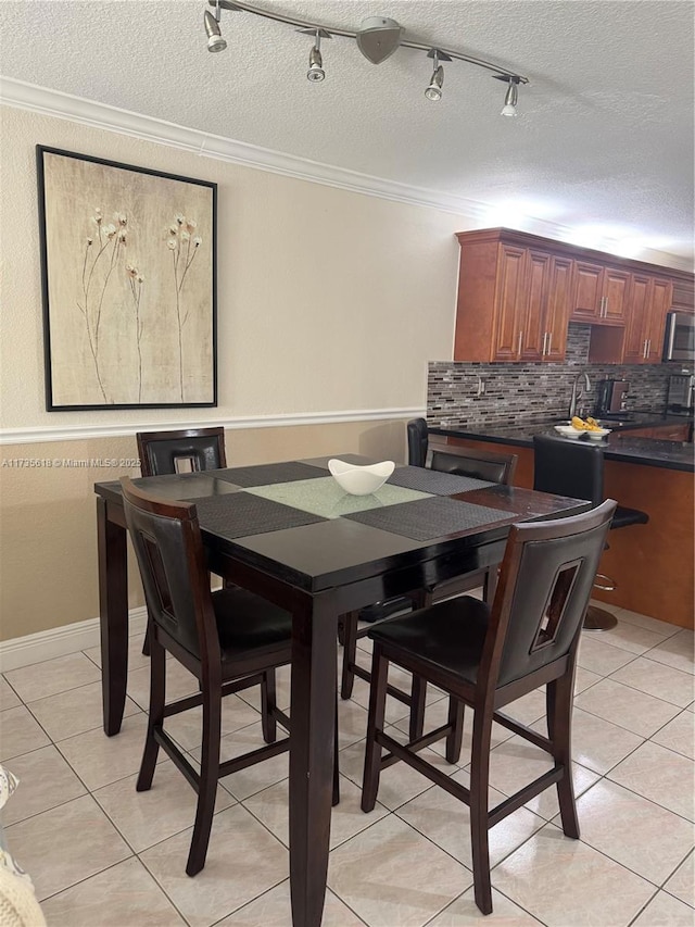 dining room featuring ornamental molding, a textured ceiling, and light tile patterned floors