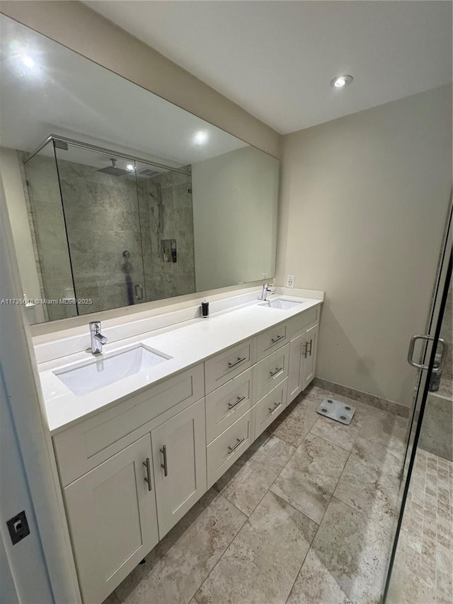 full bathroom with a stall shower, a sink, baseboards, and double vanity