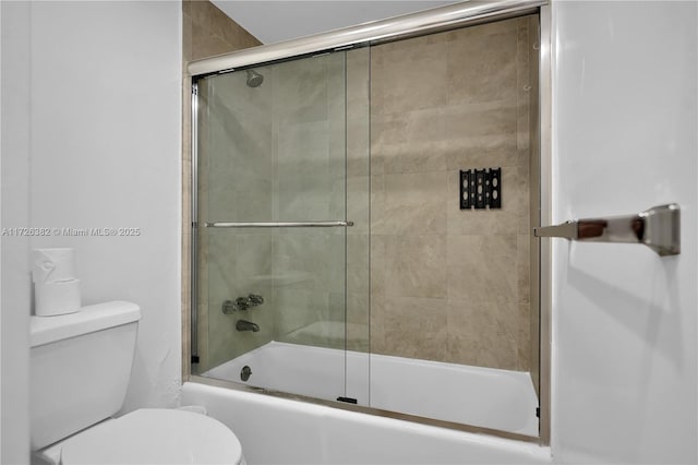 bathroom with toilet and shower / bath combination with glass door