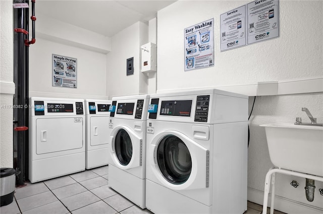 washroom with light tile patterned flooring, washer and clothes dryer, and sink