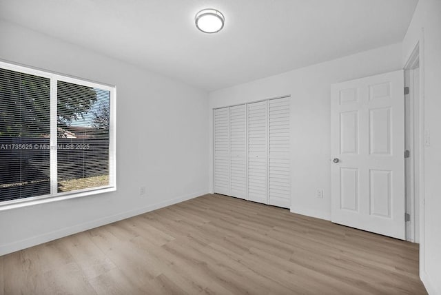 unfurnished bedroom with a closet and light wood-type flooring