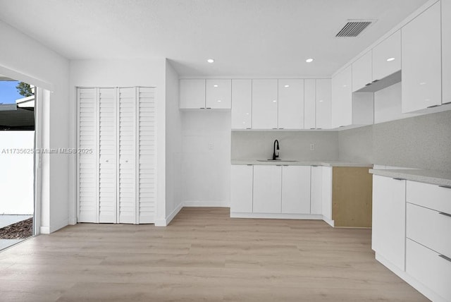 kitchen with white cabinetry, sink, and light hardwood / wood-style flooring