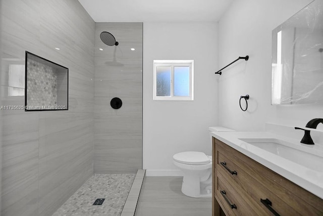 bathroom with vanity, toilet, and a tile shower