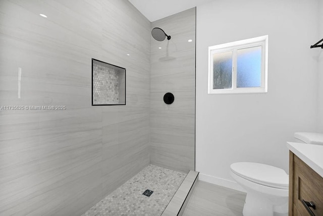 bathroom featuring vanity, toilet, and a tile shower