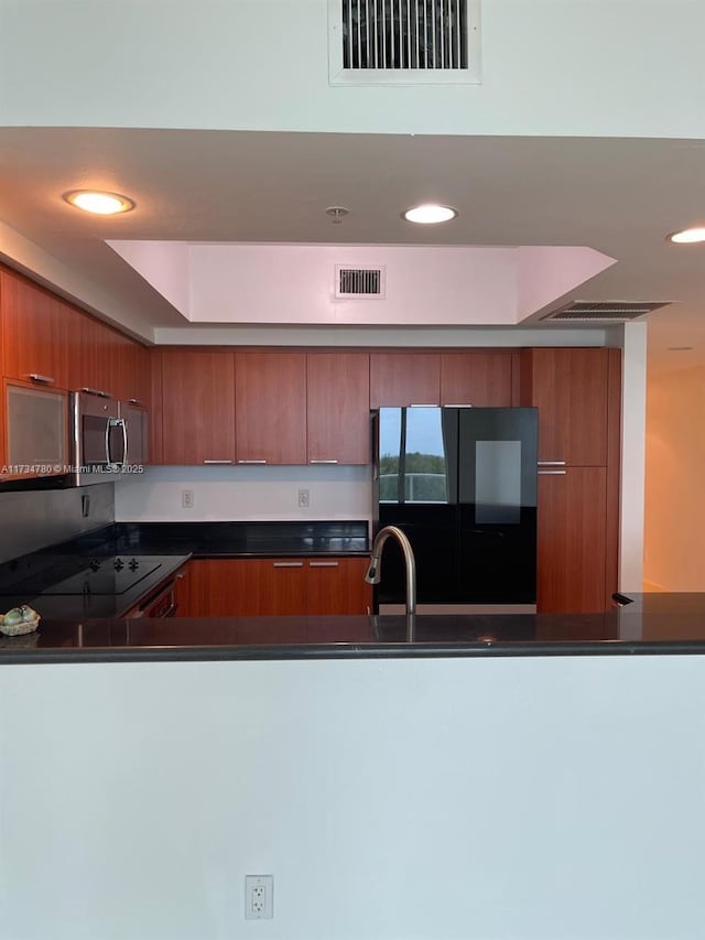 kitchen with black refrigerator, sink, and range