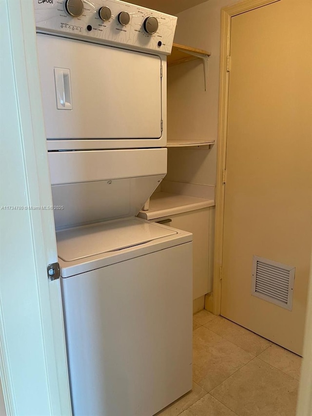 washroom with stacked washer / drying machine and light tile patterned floors