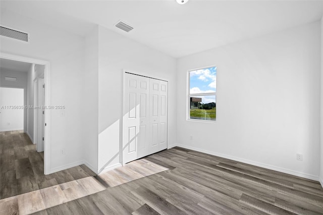 unfurnished bedroom with dark hardwood / wood-style flooring and a closet