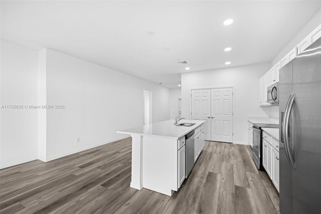 kitchen featuring dark wood-type flooring, sink, stainless steel appliances, a kitchen island with sink, and white cabinets