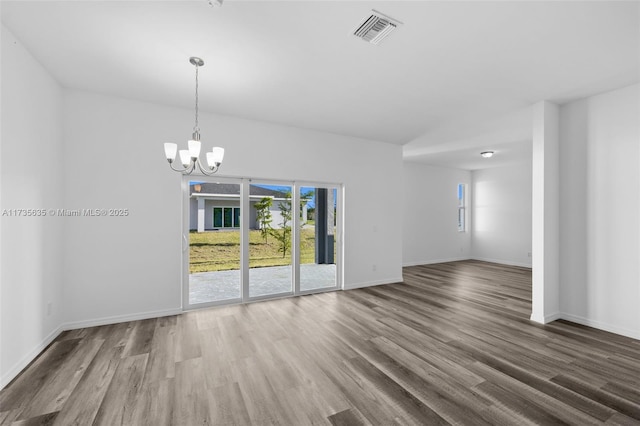 spare room featuring wood-type flooring and a notable chandelier