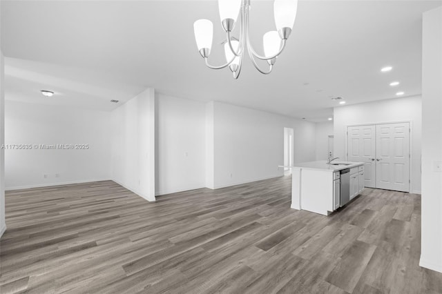 unfurnished living room with hardwood / wood-style flooring, sink, and an inviting chandelier