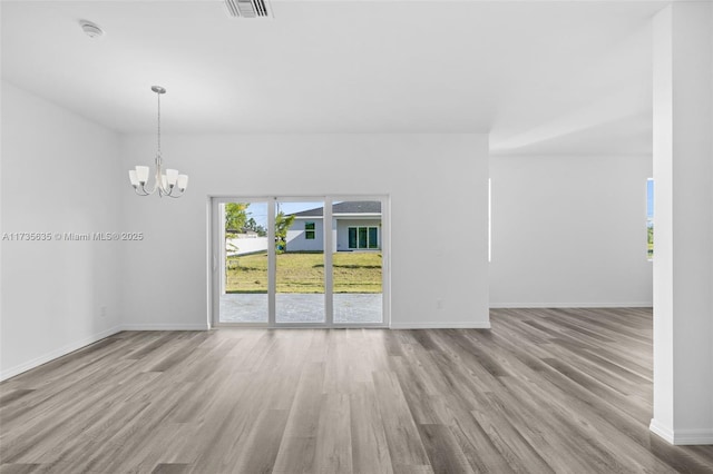 empty room featuring a chandelier and light wood-type flooring