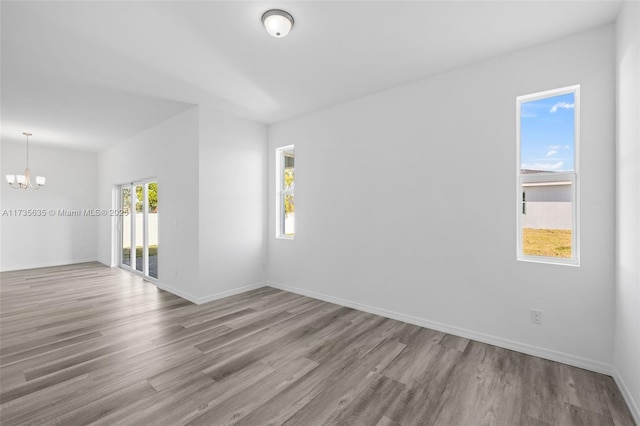 spare room with an inviting chandelier and light wood-type flooring