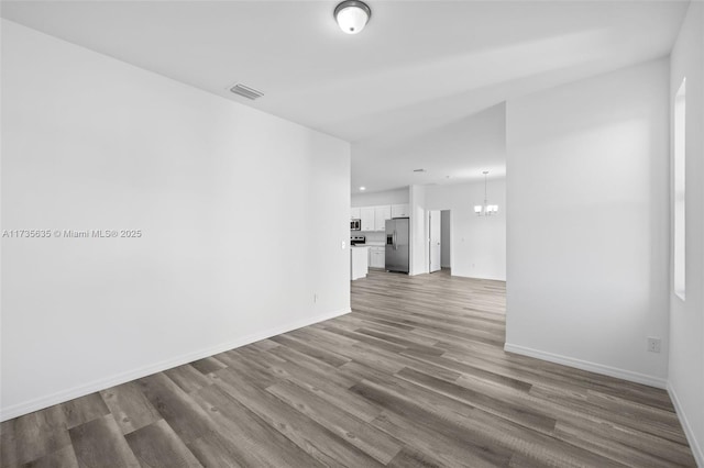 empty room featuring wood-type flooring and a chandelier