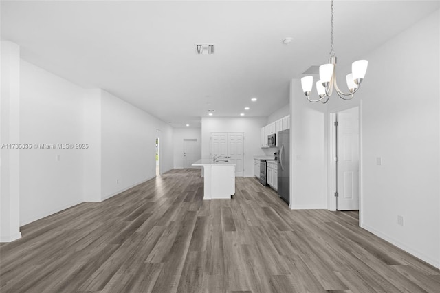 kitchen featuring pendant lighting, white cabinets, a center island, stainless steel appliances, and dark wood-type flooring