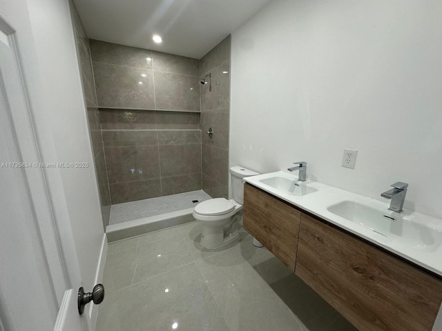 bathroom featuring tile patterned flooring, vanity, tiled shower, and toilet