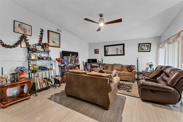 living room with light hardwood / wood-style flooring, ceiling fan, vaulted ceiling, and a textured ceiling