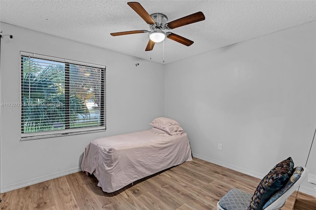 bedroom featuring ceiling fan, light hardwood / wood-style flooring, and a textured ceiling