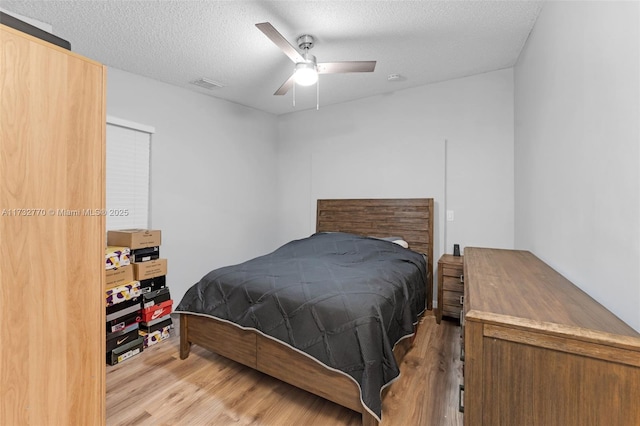 bedroom with ceiling fan, a textured ceiling, and light hardwood / wood-style floors