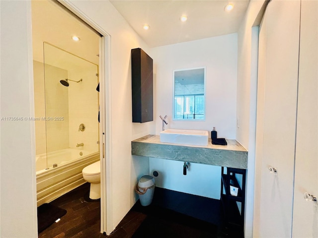 full bathroom featuring tiled shower / bath, hardwood / wood-style flooring, sink, and toilet