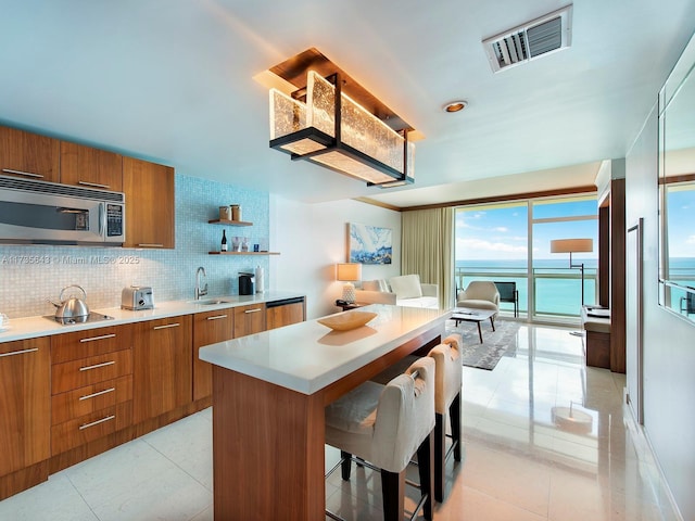 kitchen with a kitchen island, tasteful backsplash, sink, a kitchen breakfast bar, and a water view