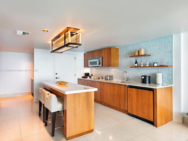 kitchen featuring sink, dishwasher, backsplash, a kitchen island, and light tile patterned flooring