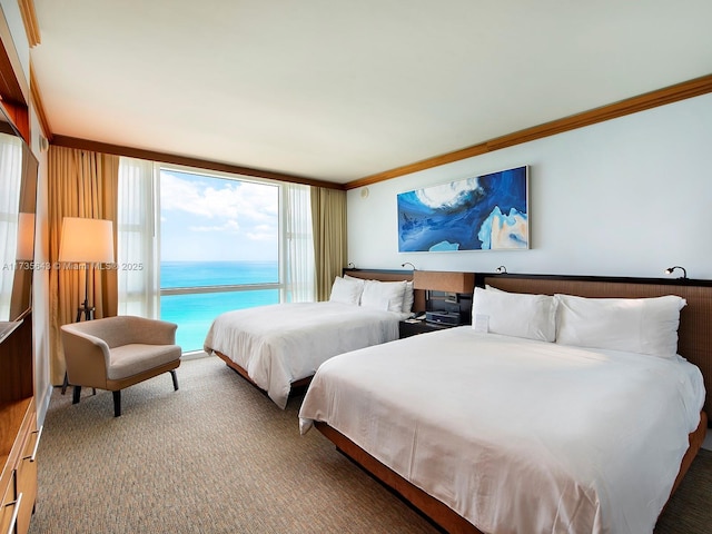 bedroom featuring crown molding, a water view, carpet floors, and a wall of windows