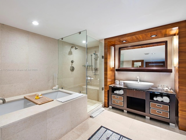 bathroom with tile patterned floors, separate shower and tub, tile walls, and vanity