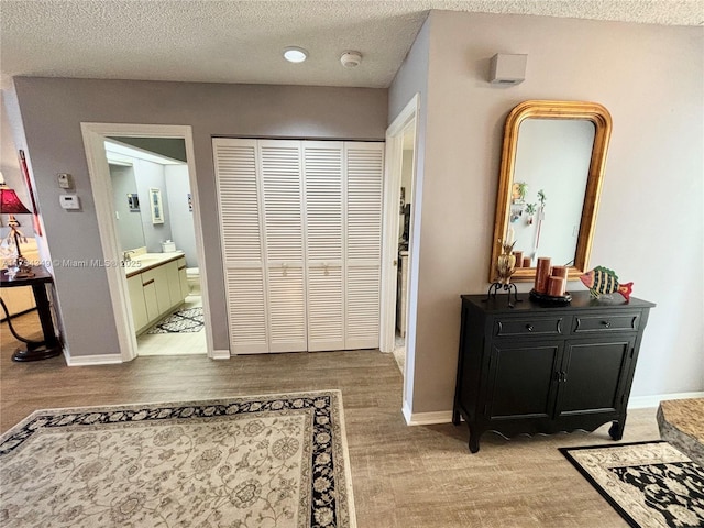 hallway with sink, a textured ceiling, and light wood-type flooring