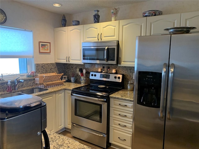 kitchen featuring stainless steel appliances, white cabinetry, and sink