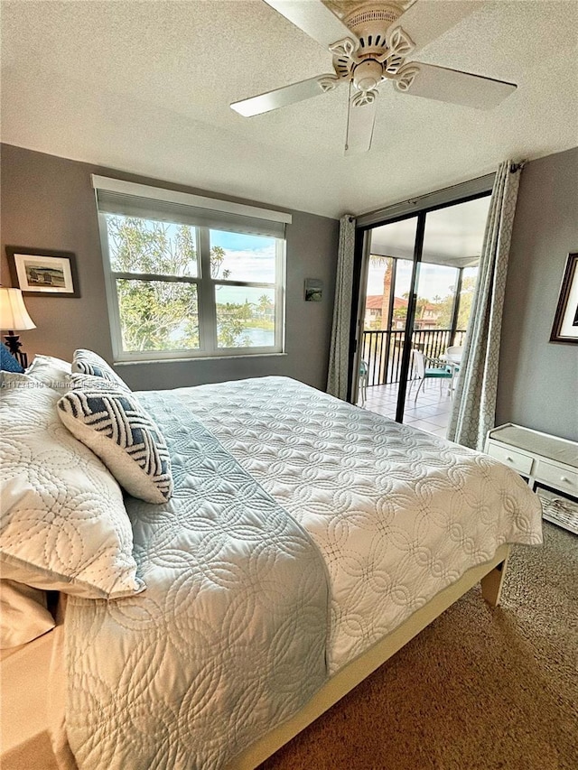 bedroom with ceiling fan, carpet flooring, a textured ceiling, and access to outside