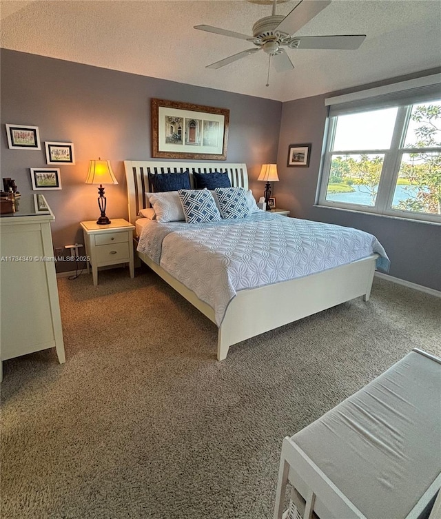 bedroom with ceiling fan, carpet, and a textured ceiling