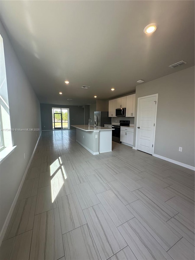 kitchen featuring white cabinetry, appliances with stainless steel finishes, and a kitchen island with sink