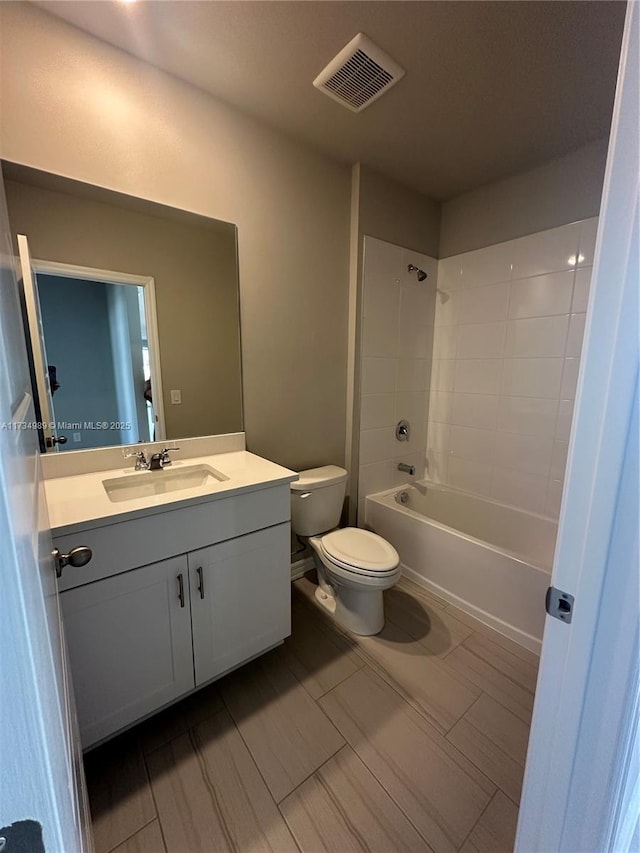 full bathroom with tiled shower / bath, vanity, and toilet