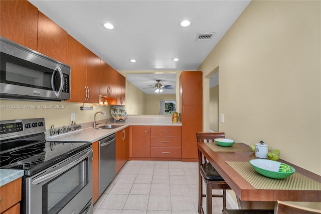 kitchen featuring appliances with stainless steel finishes, sink, light tile patterned floors, and ceiling fan