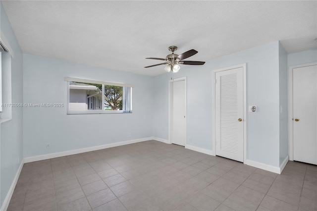 unfurnished bedroom with multiple closets, ceiling fan, light tile patterned flooring, and a textured ceiling