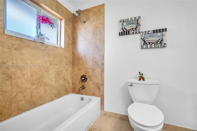 bathroom featuring tile patterned flooring, tiled shower / bath combo, and toilet