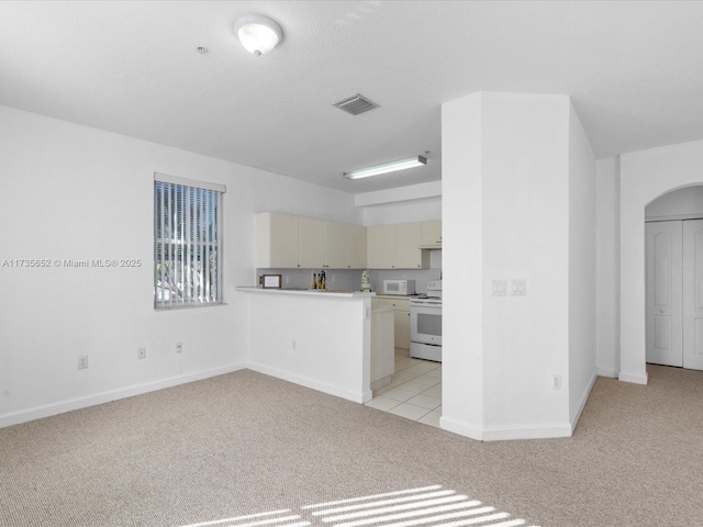 kitchen featuring light carpet, kitchen peninsula, white appliances, and cream cabinetry