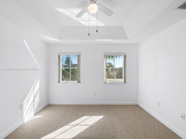 unfurnished room with ceiling fan, carpet flooring, a healthy amount of sunlight, and a tray ceiling