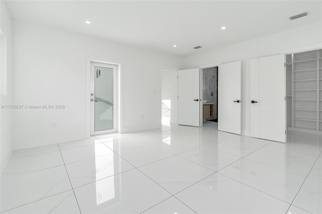 unfurnished bedroom with light tile patterned floors, a spacious closet, and a closet